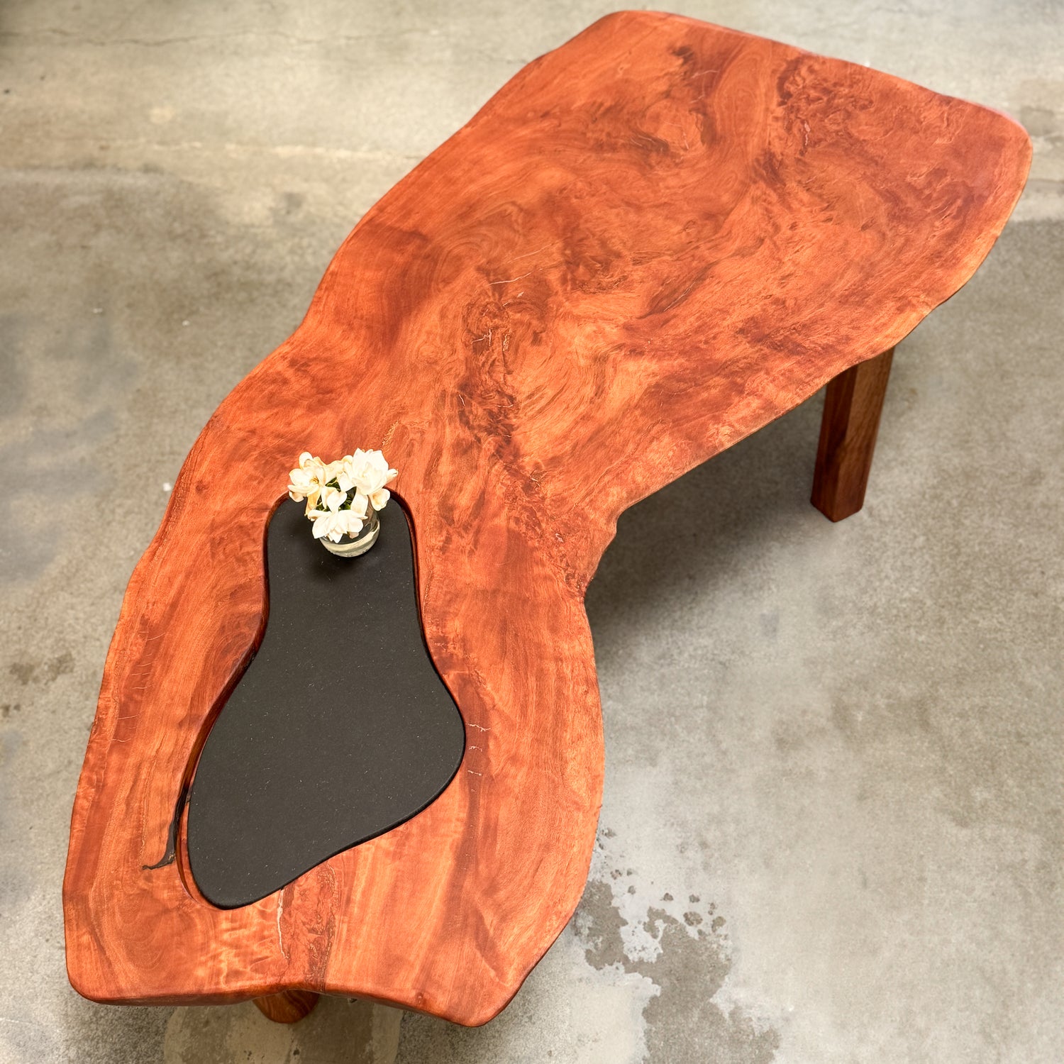 Wooden coffee table with a black inset on a concrete floor