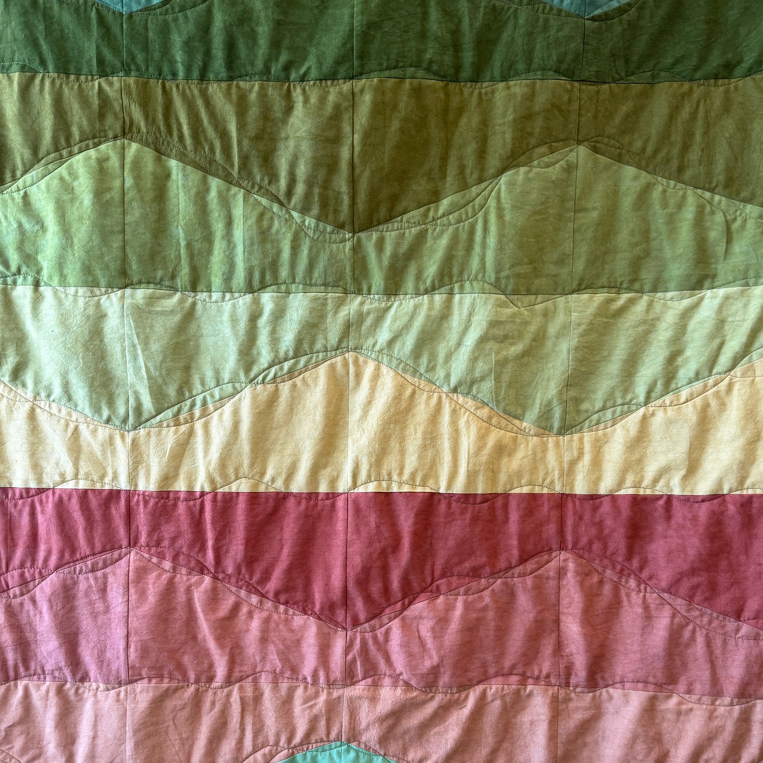 Quilt with wavy pattern in green, yellow, and pink