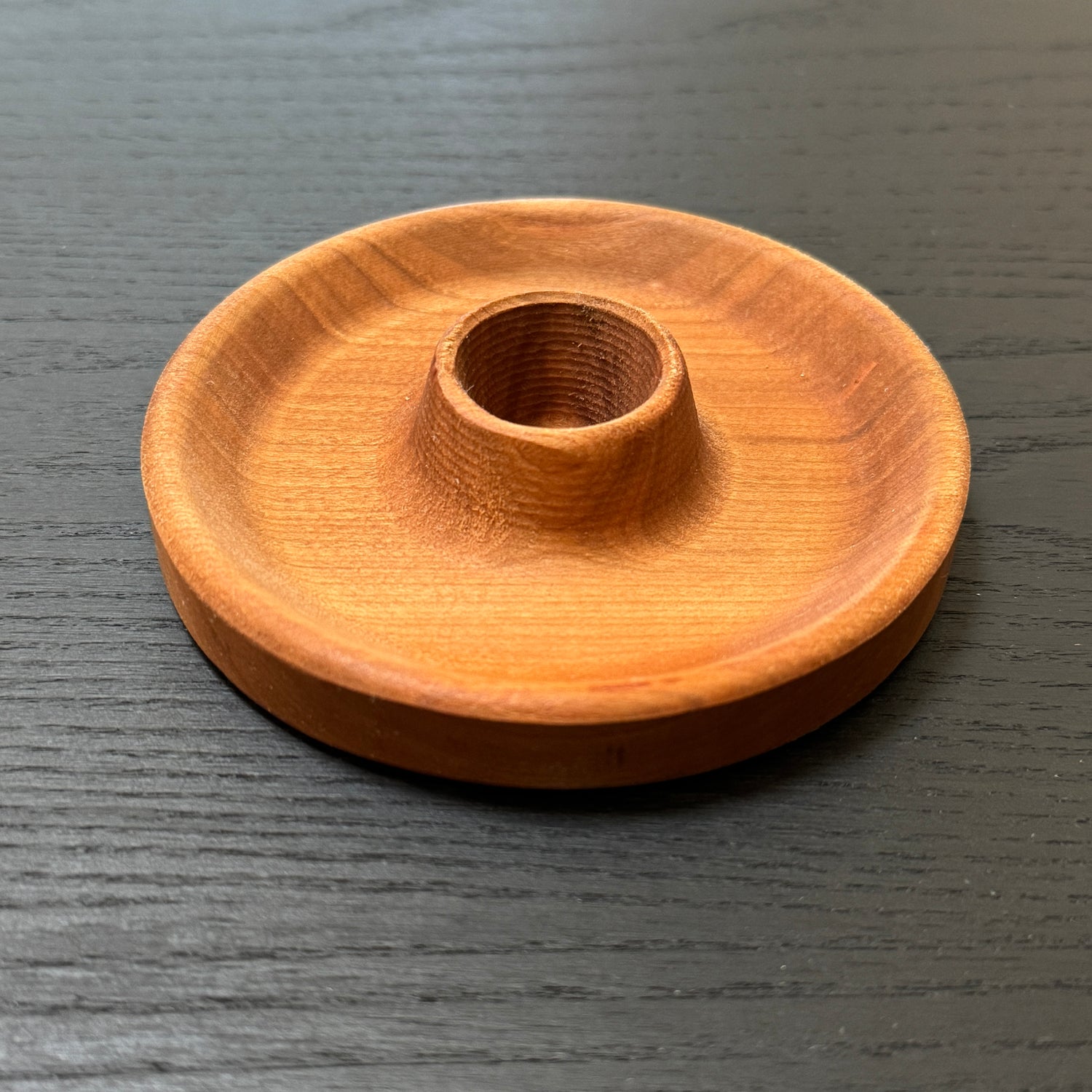 Wooden candle holder on a dark wooden surface
