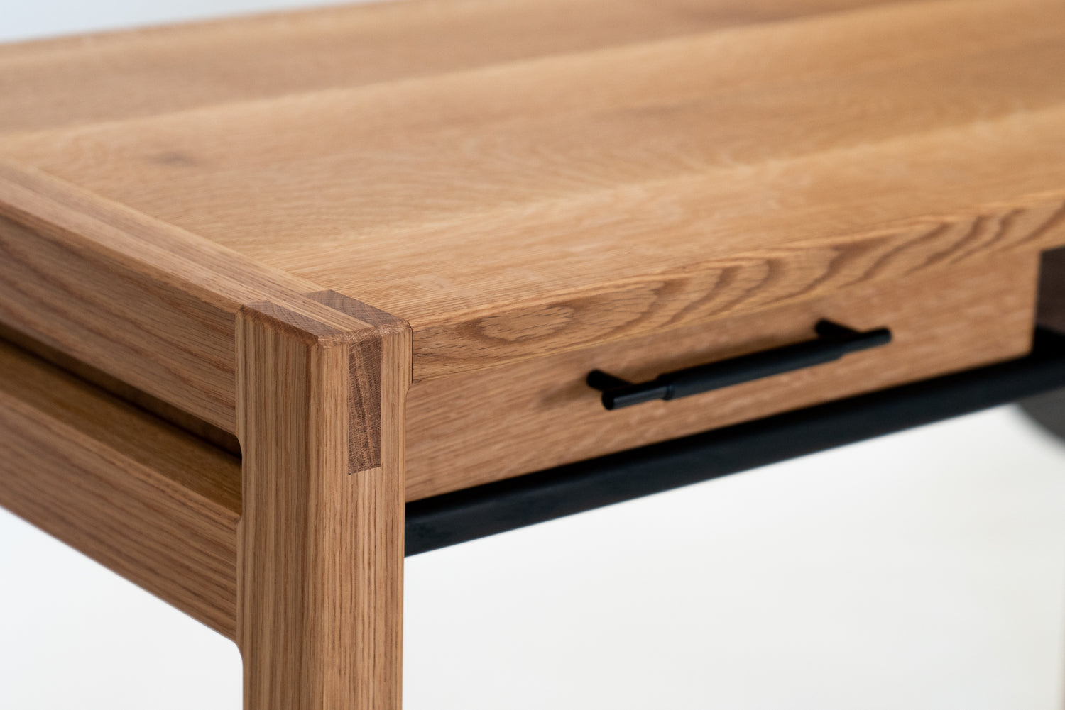 Front corner view of the Kamehana Desk built in White Oak with Black Knurled Drawer Pull