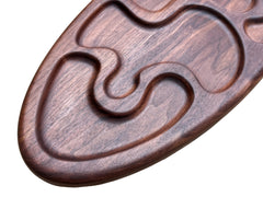 A close-up of a dark brown wooden tray (made of walnut) with carved wavy pattern.