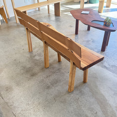 Wooden bench on a concrete floor with a wooden table in the background
