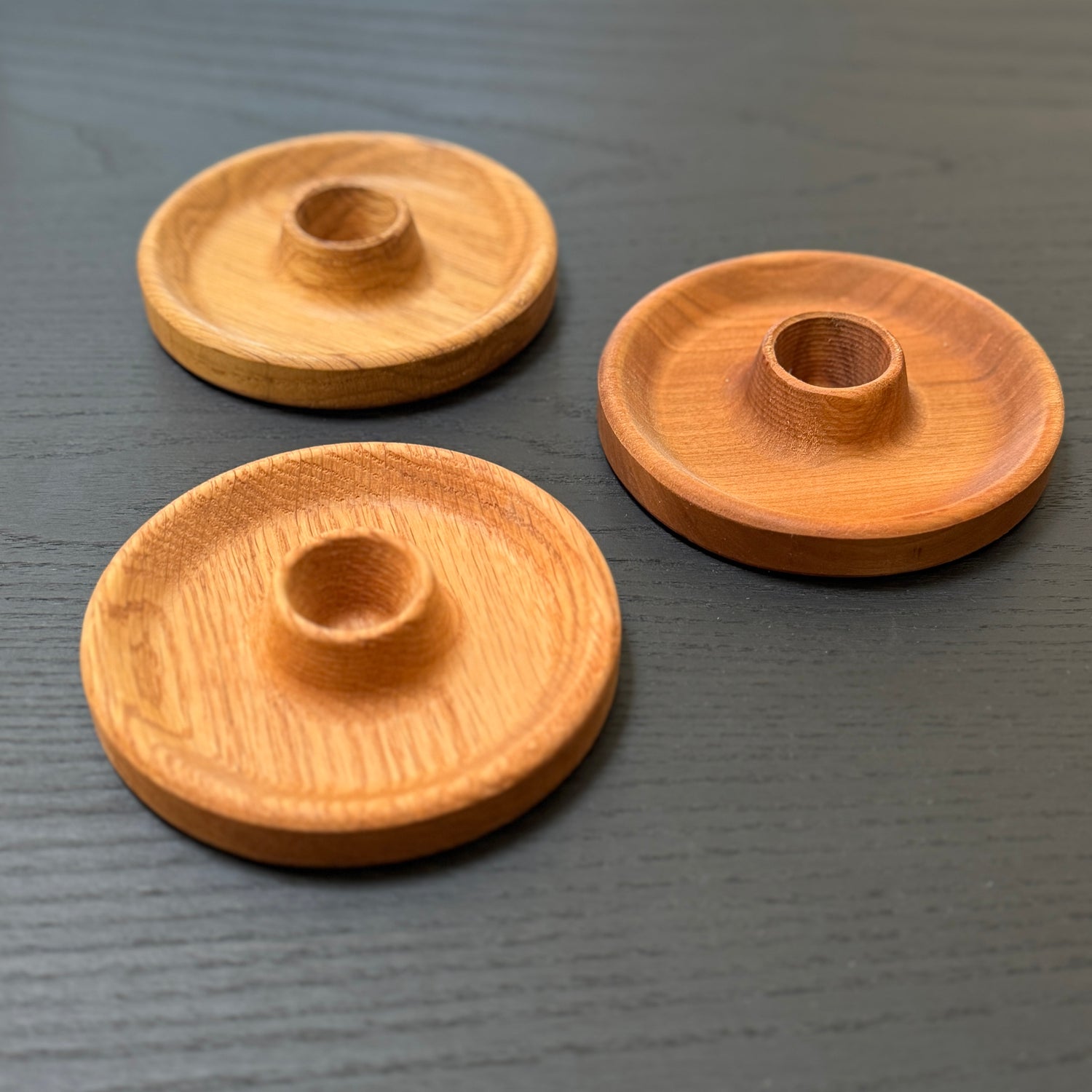 Three wooden candle holders on a dark surface